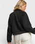 Person wearing a black jacket and white pants on a light gray background