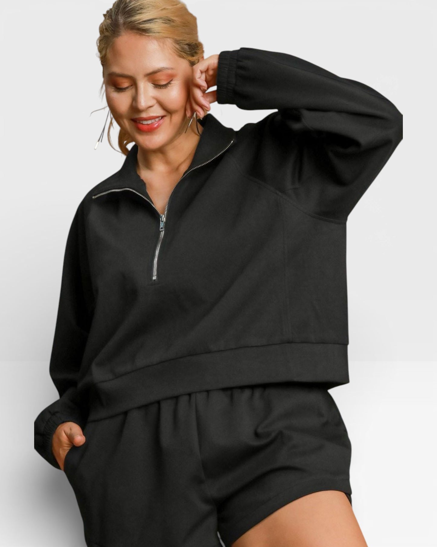 Woman wearing a black tracksuit against a light gray background