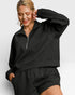 Woman wearing a black tracksuit against a light gray background