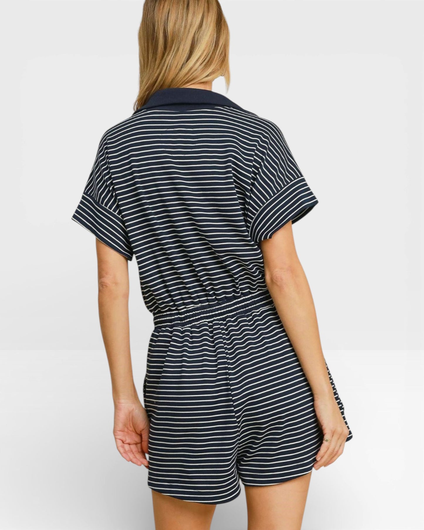 Person wearing a black and white striped romper on a plain background