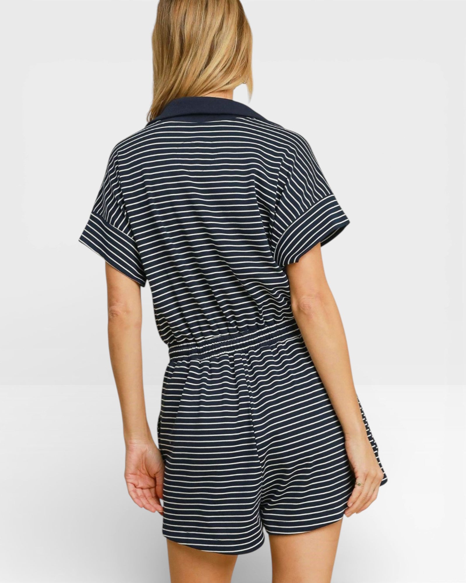 Person wearing a black and white striped romper on a plain background