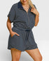 Woman wearing a navy and white striped romper on a plain background