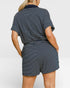 Person wearing a navy and white striped romper on a plain background