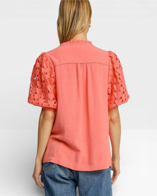 Woman wearing a coral blouse with ruffled sleeves on a white background