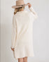 Person wearing a cream-colored sweater dress and beige hat on a plain background