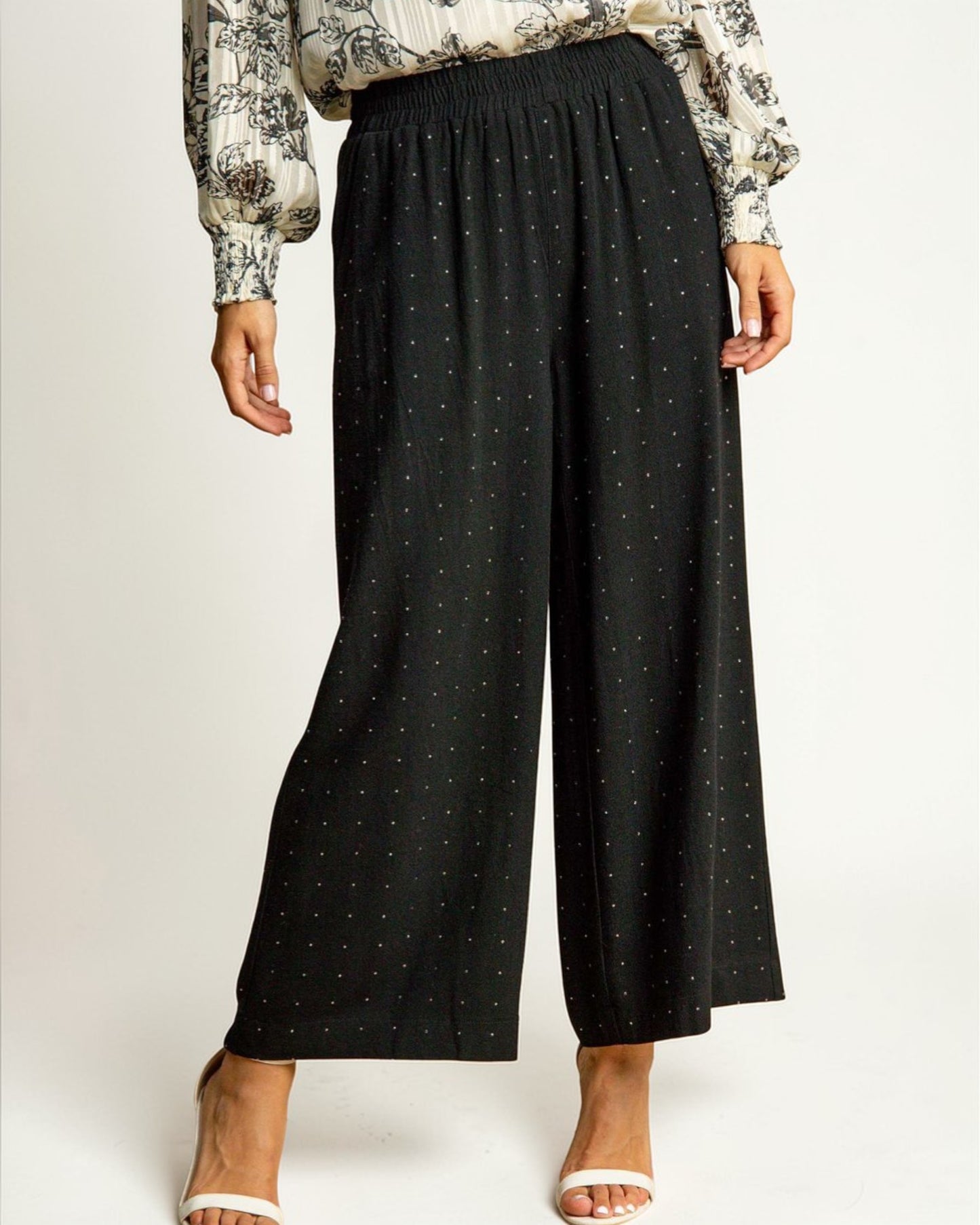 Person wearing black wide-leg pants with a subtle pattern on a white background