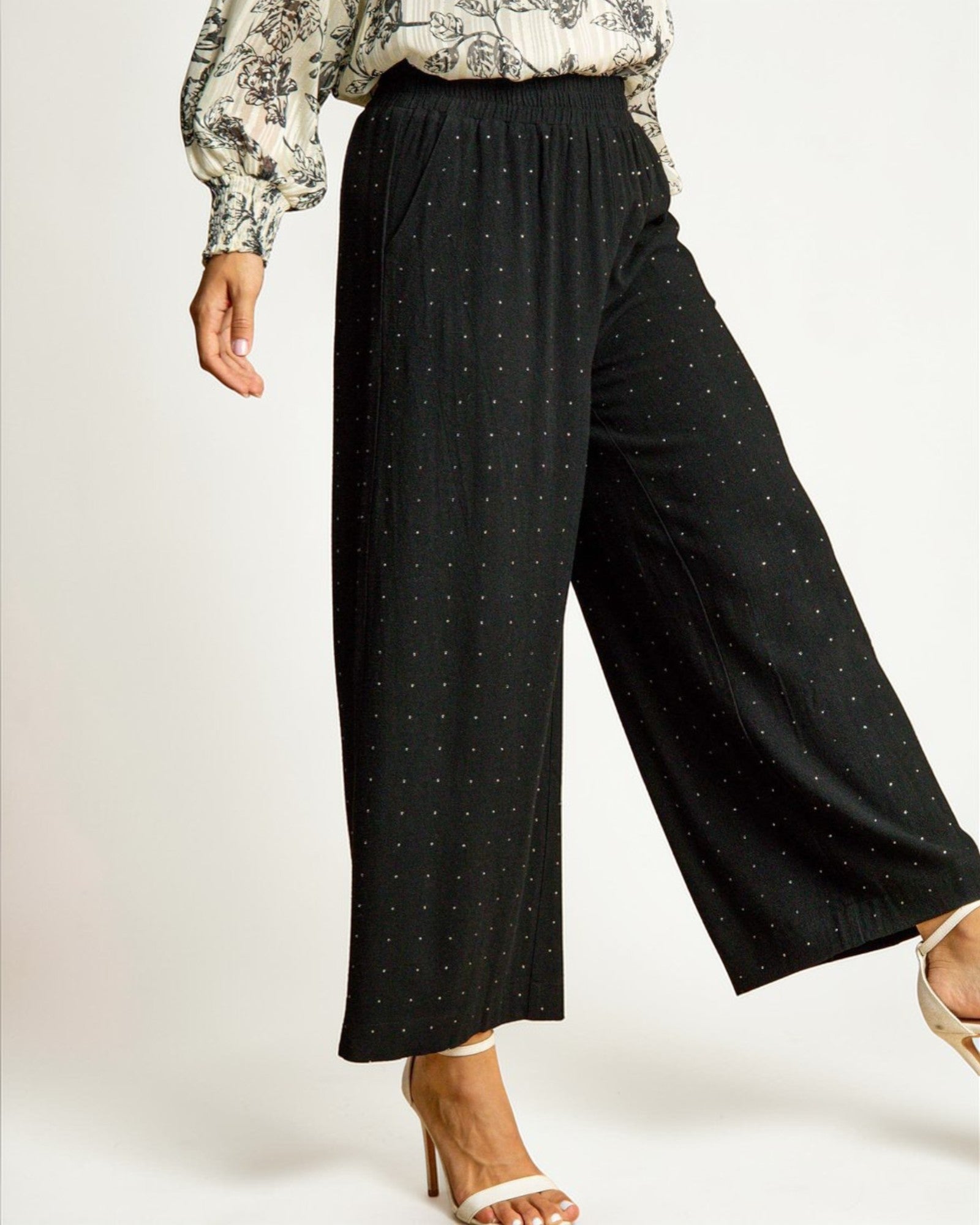 Person wearing black wide-leg pants with a subtle pattern on a white background