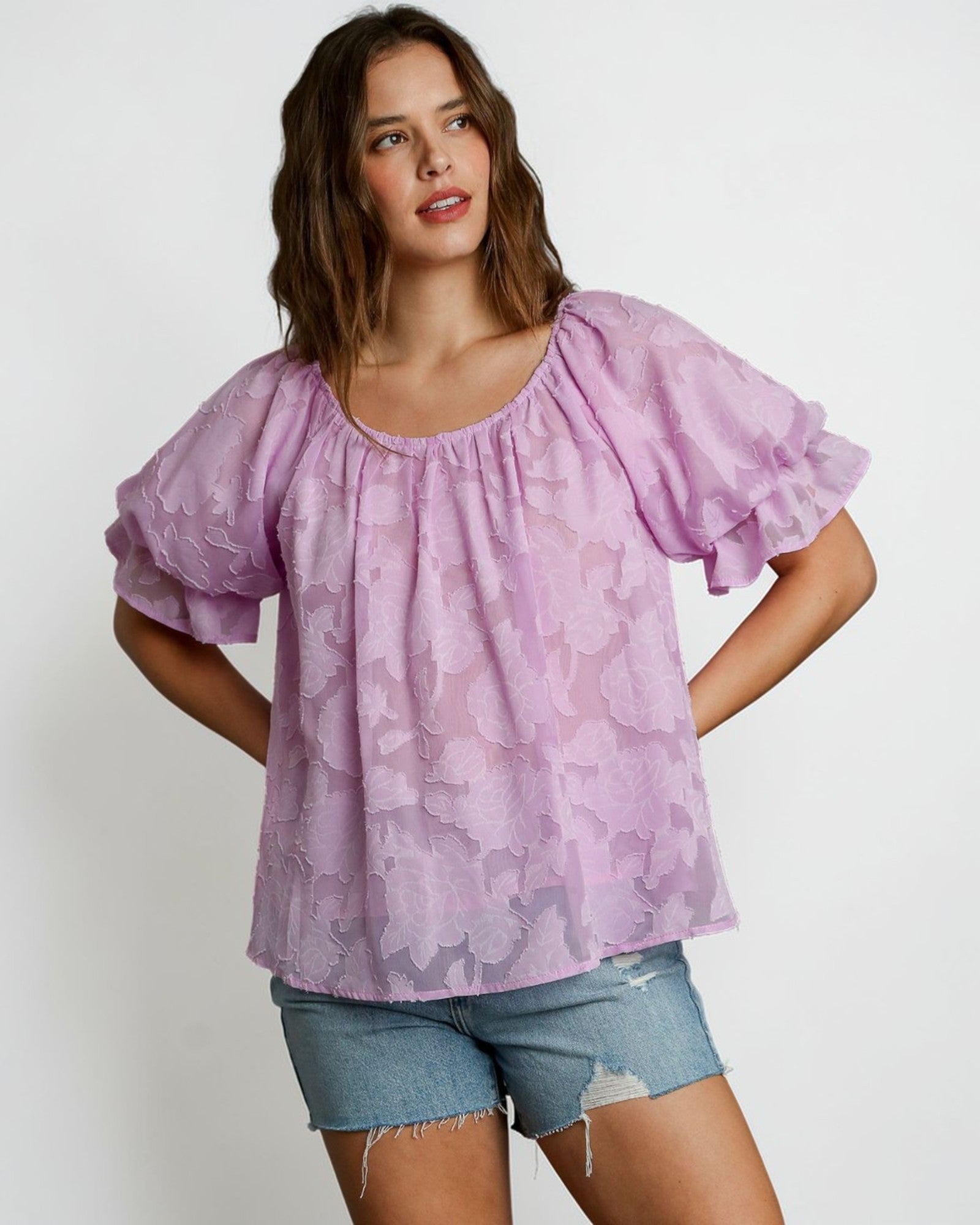 Woman wearing a light purple blouse with ruffled sleeves on a white background