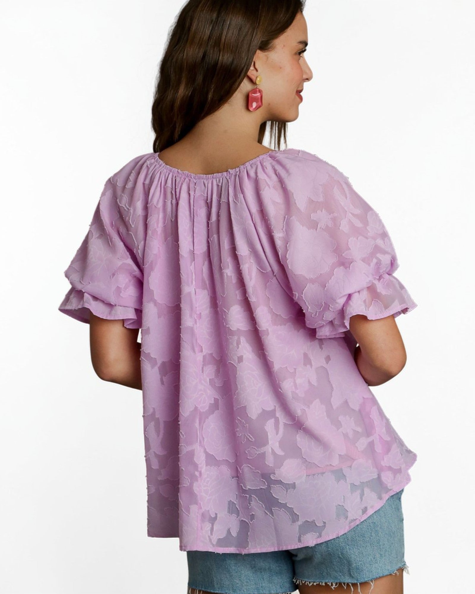 Woman wearing a pink floral blouse with ruffled sleeves on a white background