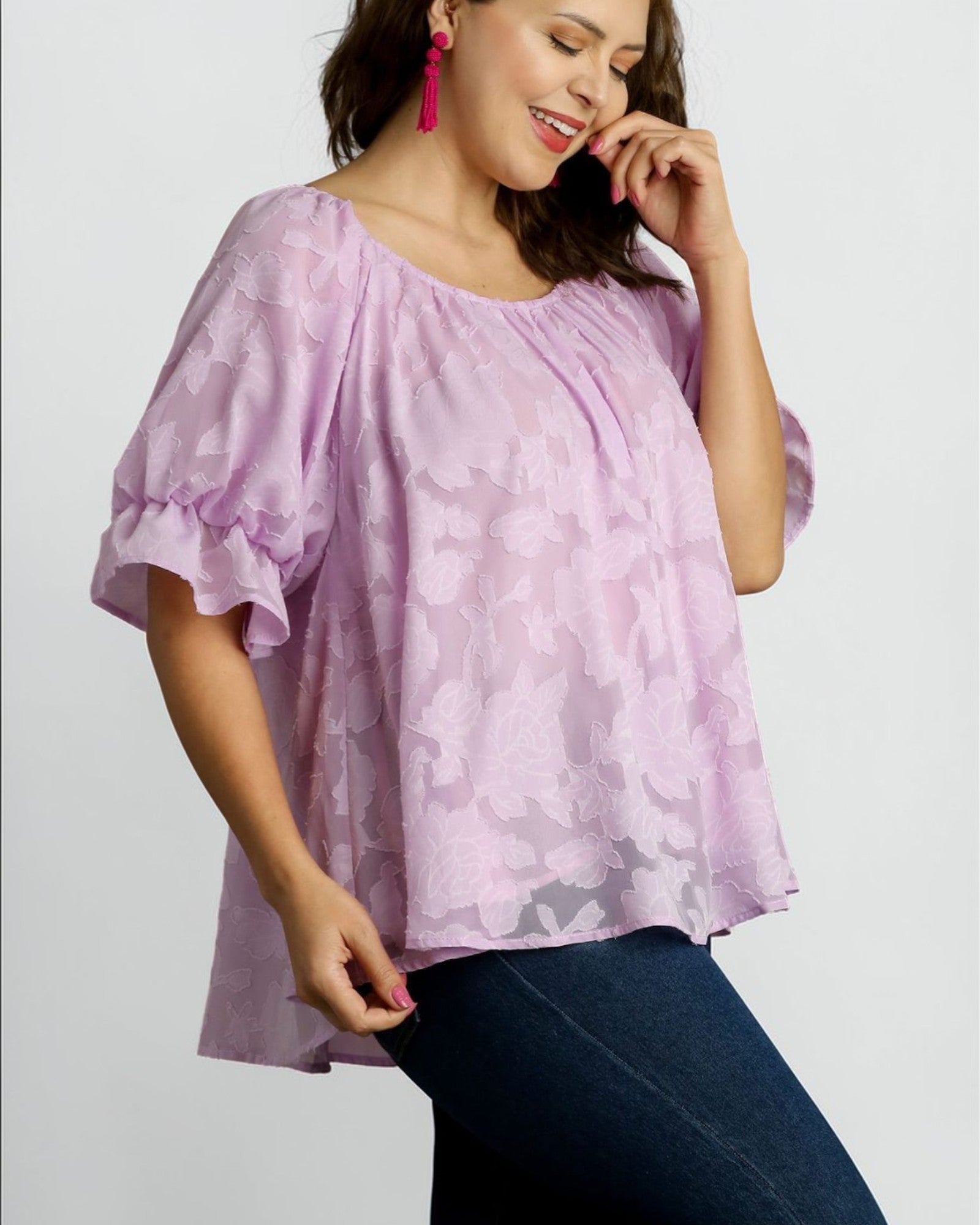 Woman wearing a light purple blouse with a subtle pattern on a plain background