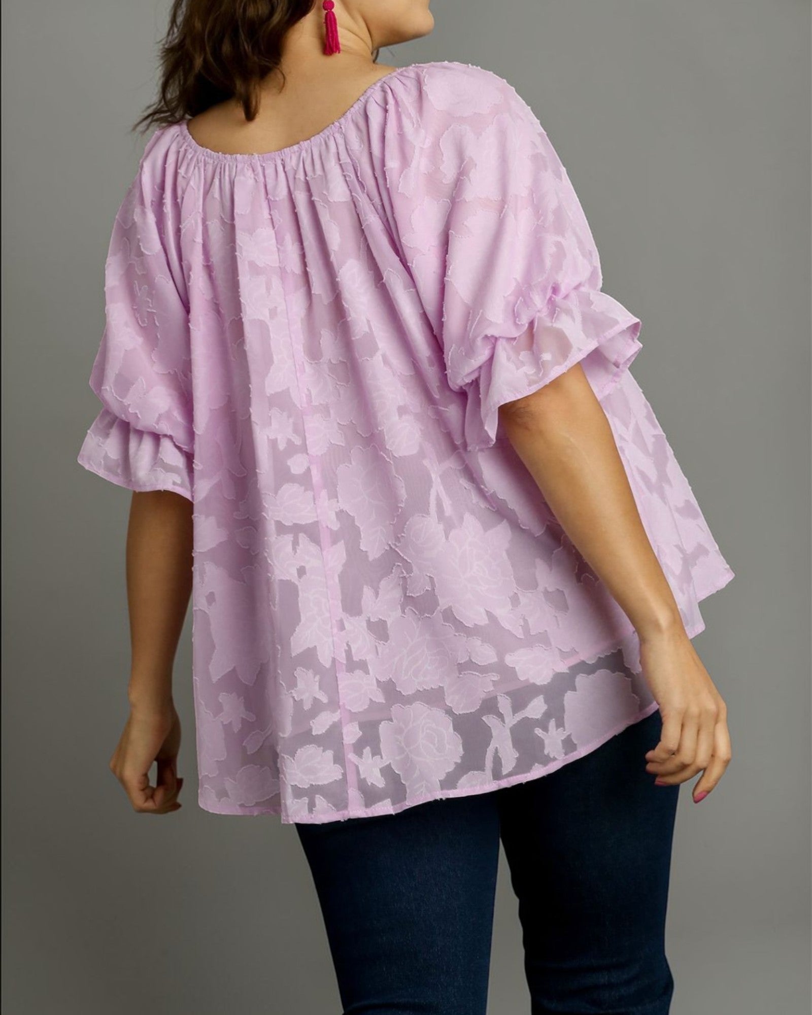 Woman wearing a light purple blouse with a subtle pattern on a gray background