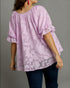 Woman wearing a light purple blouse with a subtle pattern on a gray background