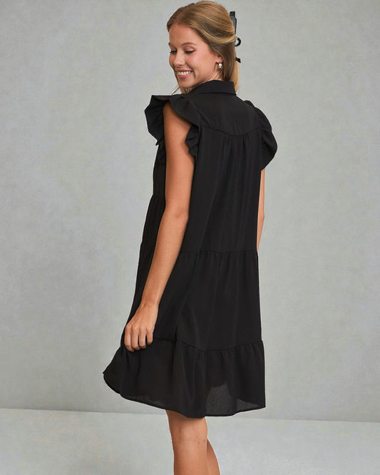 Woman wearing a black dress with ruffled details on a gray background