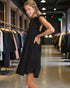 Woman trying on a black dress in a clothing store.