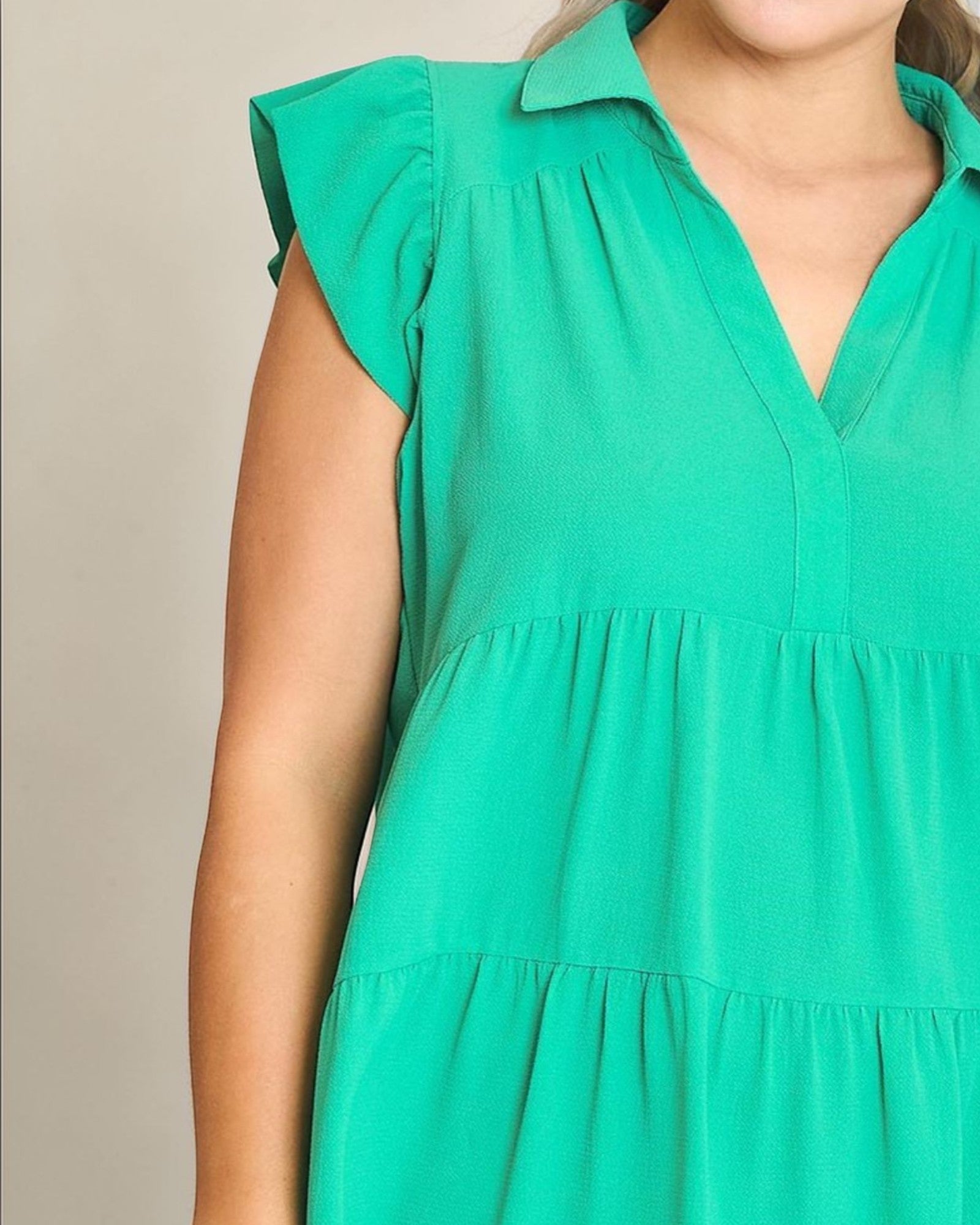 Green dress with ruffled sleeves on a neutral background