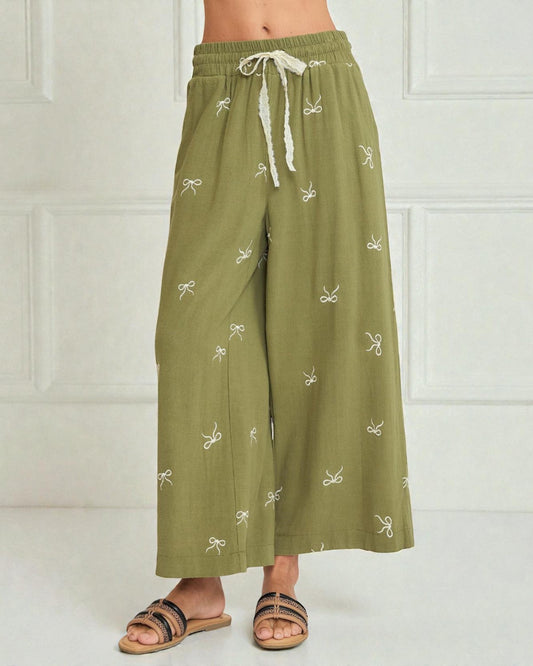 Green wide-leg pants with white patterns on a white background