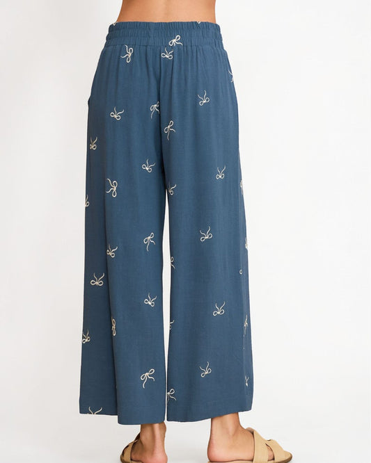 Blue pants with bow pattern worn by a person on a white background