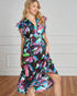 Woman wearing a colorful floral dress against a plain background