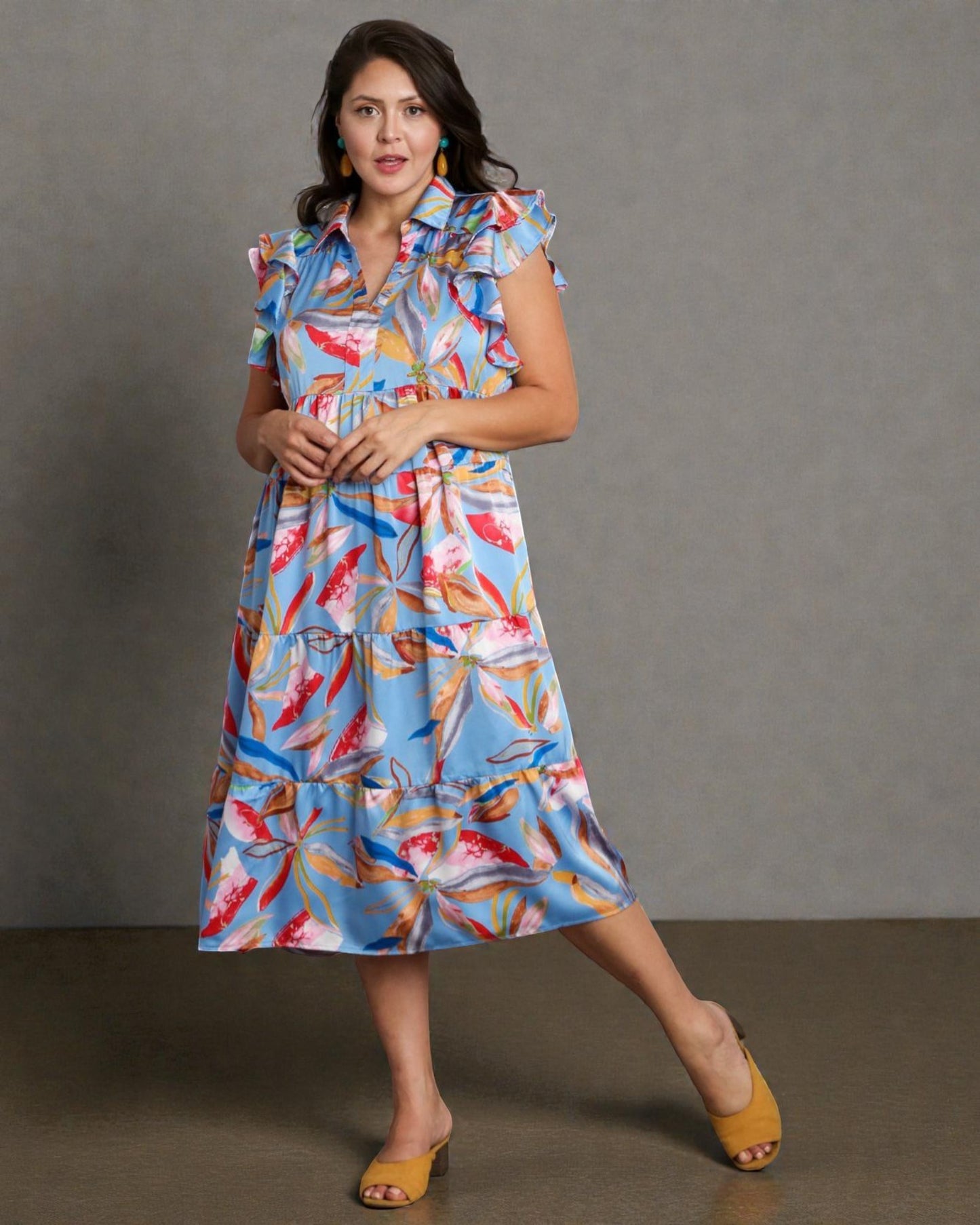 Woman wearing a colorful dress with a floral pattern against a gray background
