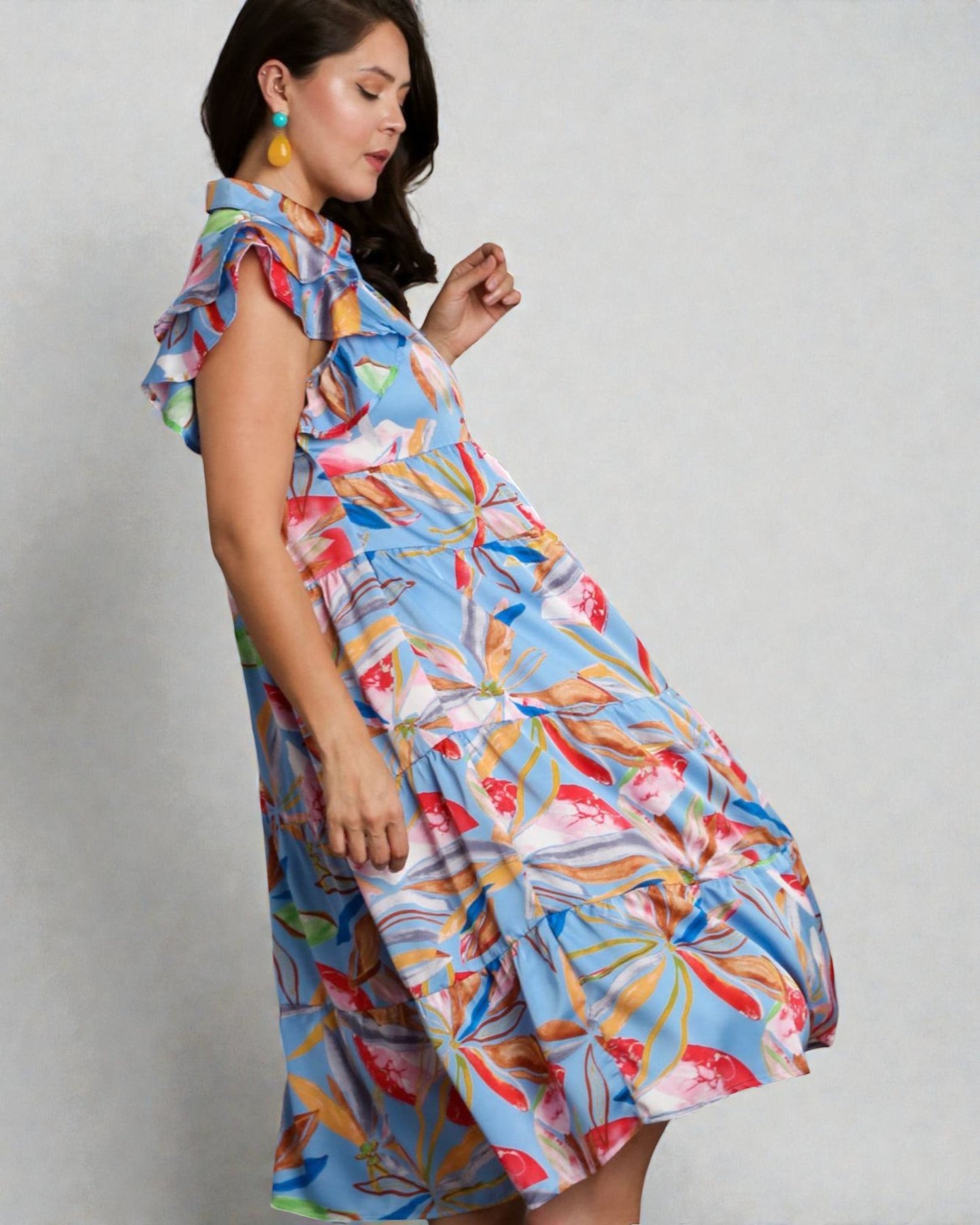 Woman wearing a colorful floral dress against a plain background