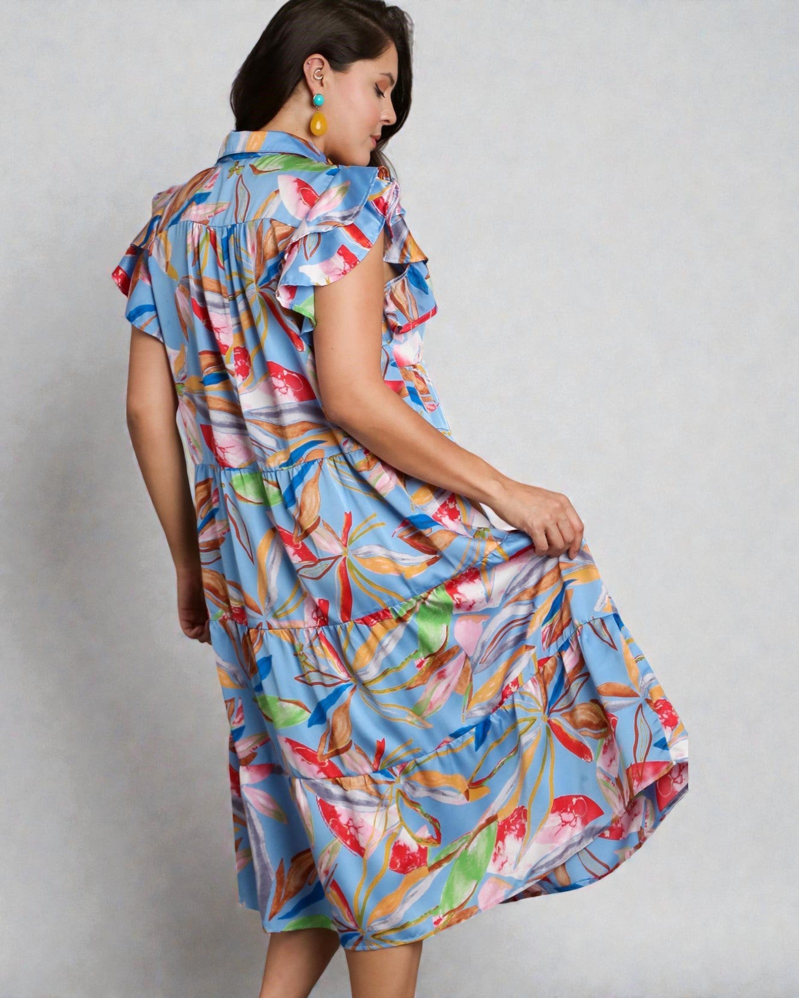 Woman wearing a colorful dress with a floral pattern on a plain background