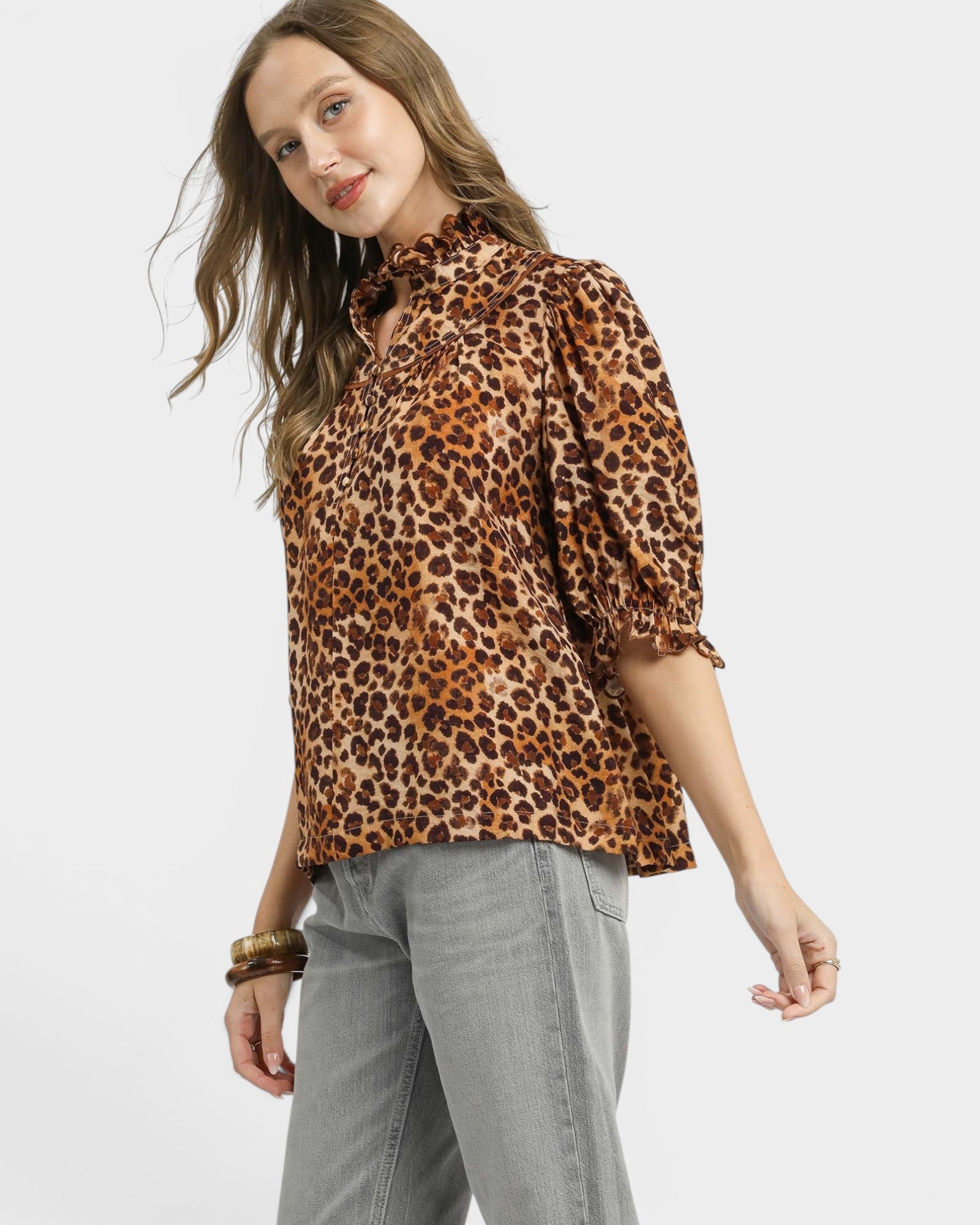 Woman wearing a leopard print blouse and gray pants on a white background