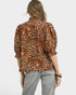 Person wearing a leopard print blouse and light gray pants on a white background
