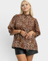 Woman wearing a leopard print blouse and black shorts on a white background