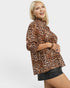 Woman wearing a leopard print top and black skirt on a white background