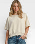 Woman wearing a beige oversized shirt and blue jeans on a white background