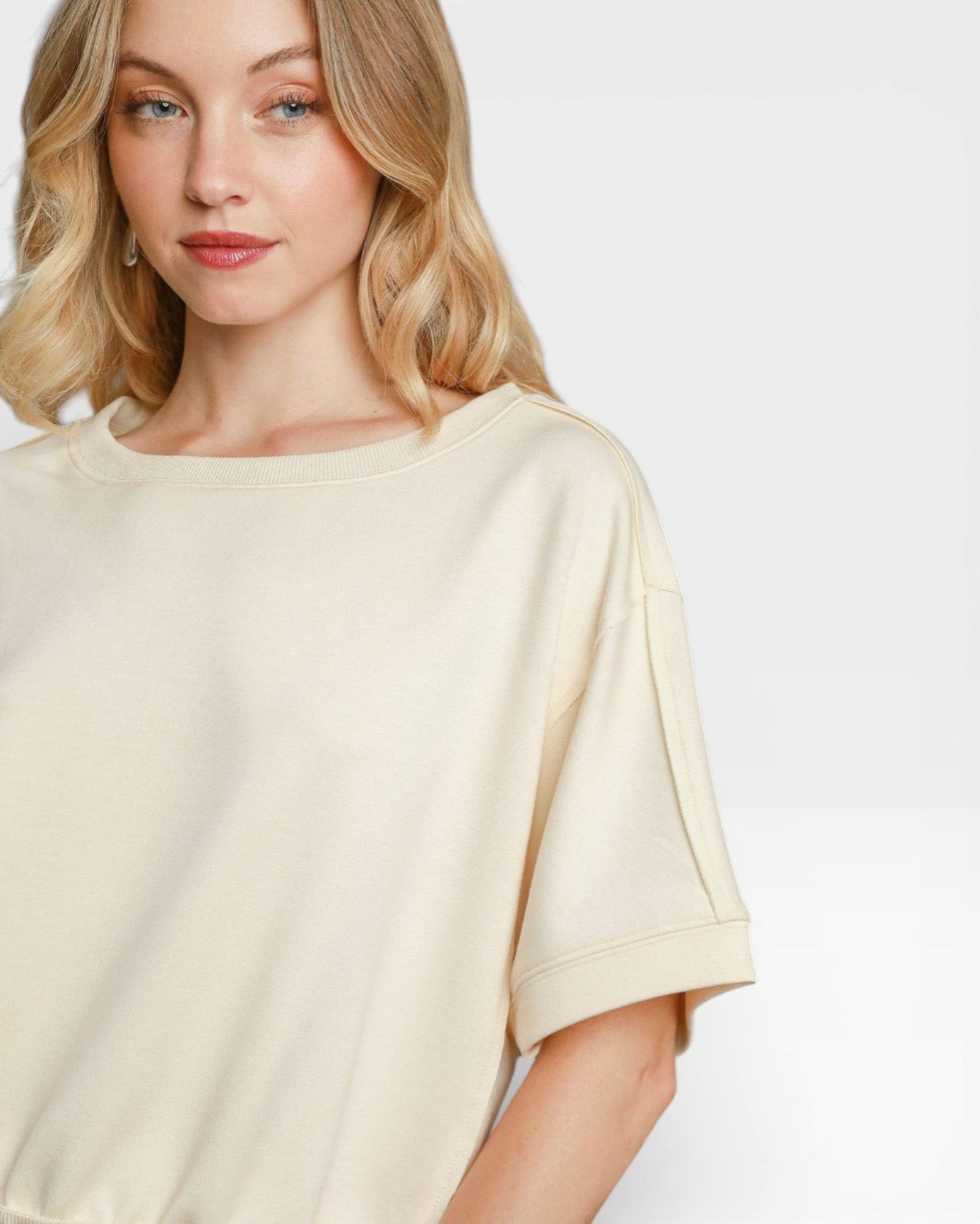 Woman wearing a beige oversized t-shirt against a plain background
