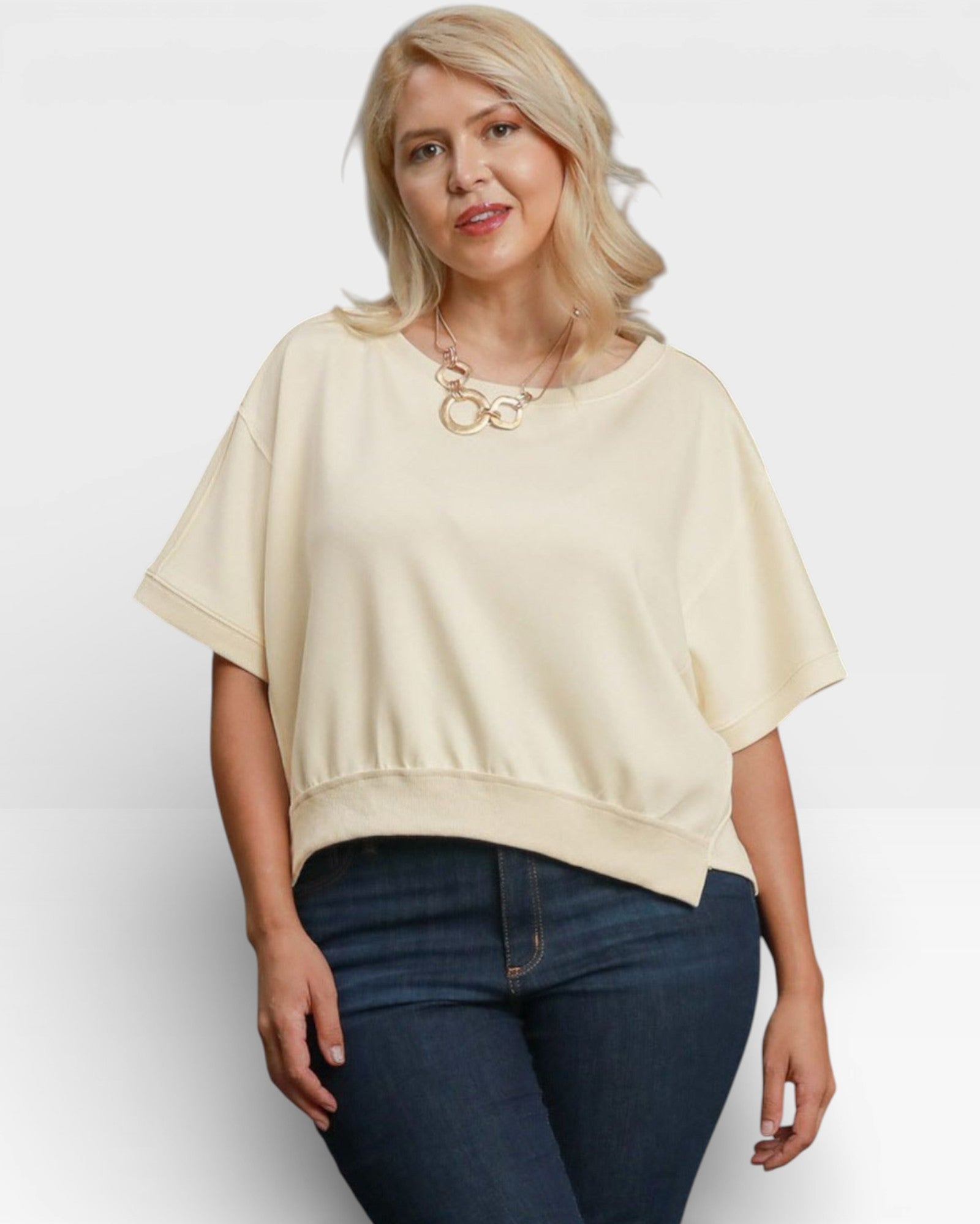 Woman wearing a beige top and blue jeans on a white background
