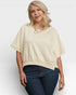 Woman wearing a beige top and blue jeans on a white background
