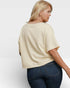Woman wearing a beige oversized t-shirt and blue jeans on a white background
