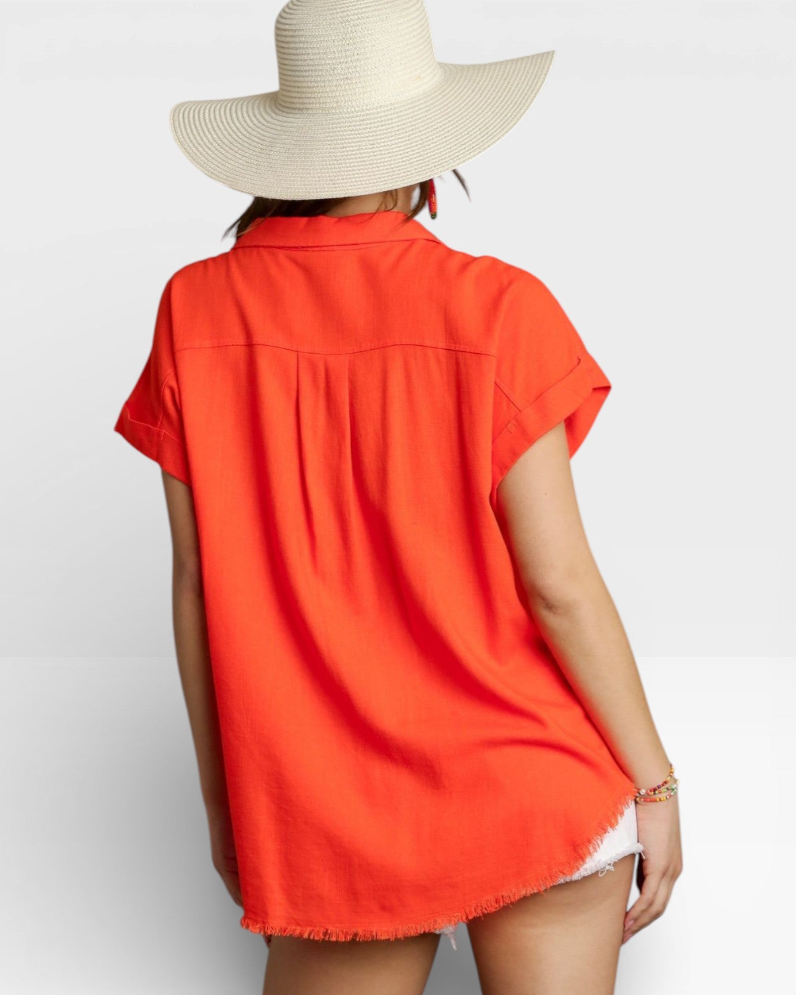 Person wearing a bright orange shirt and wide-brimmed hat on a white background