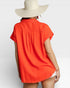 Person wearing a bright orange shirt and wide-brimmed hat on a white background