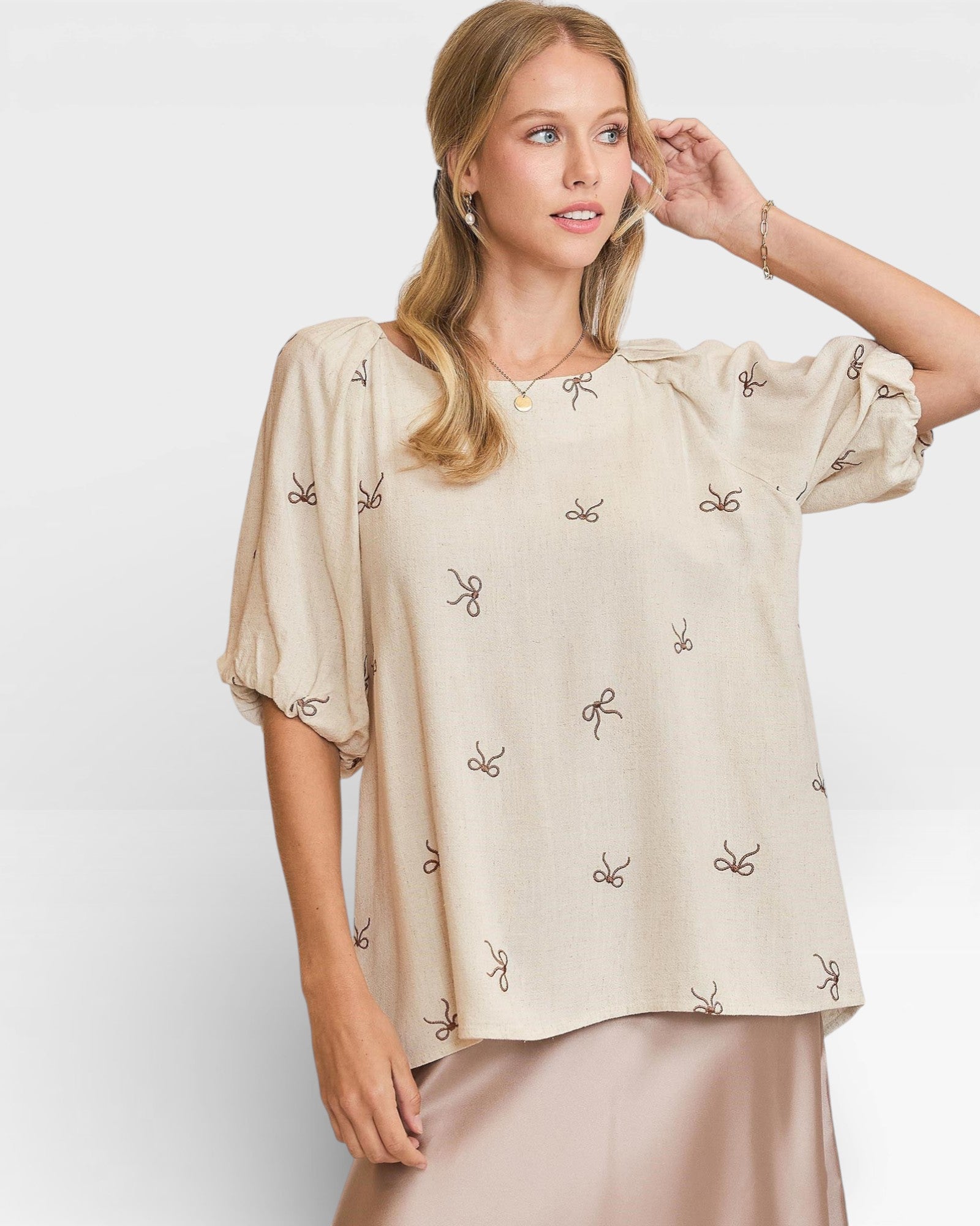 Woman wearing a beige blouse with small patterns on a white background