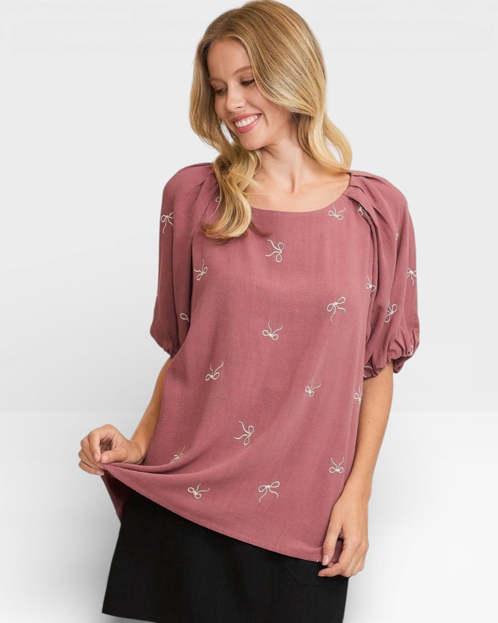 Woman wearing a mauve blouse with small patterns on a white background