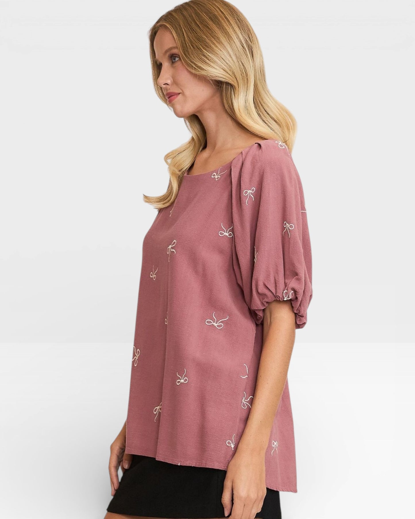 Woman wearing a pink blouse with small patterns on a white background