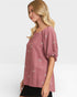Woman wearing a pink blouse with small patterns on a white background