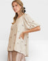 Woman wearing a beige blouse with bow patterns on a white background