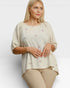 Woman wearing a beige blouse with floral embroidery on a white background