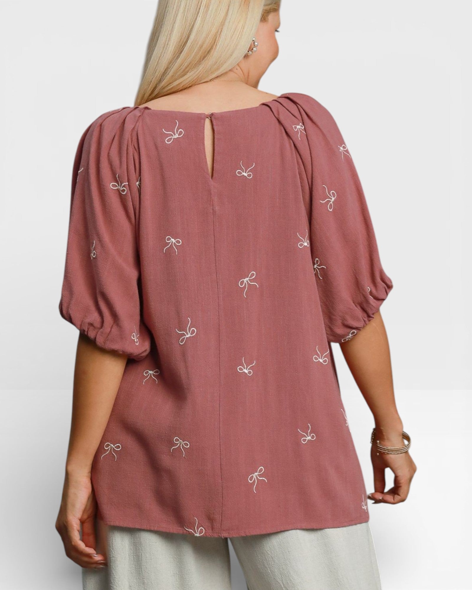 Woman wearing a pink blouse with bow patterns on a white background