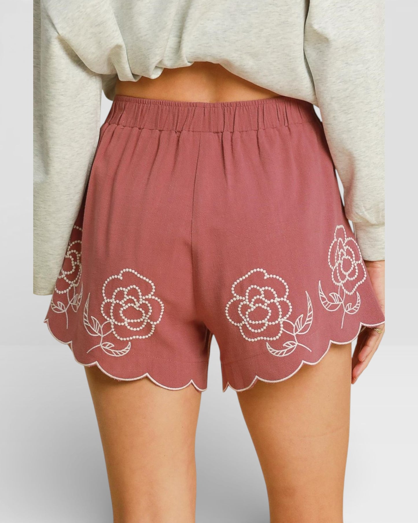 Pink shorts with floral embroidery on a plain background