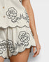 White dress with black floral embroidery on a plain background