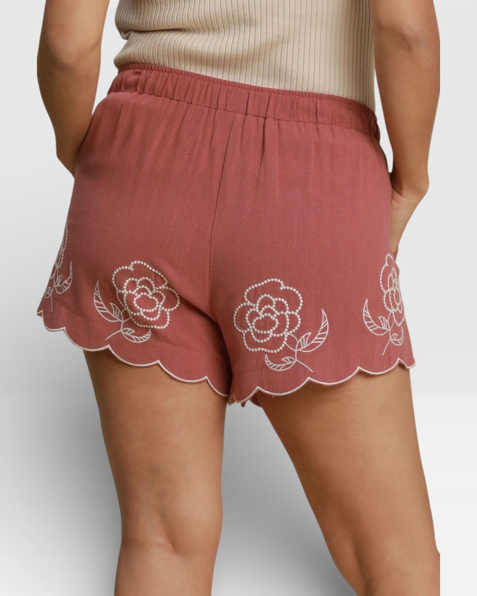 Red shorts with floral embroidery on a plain background