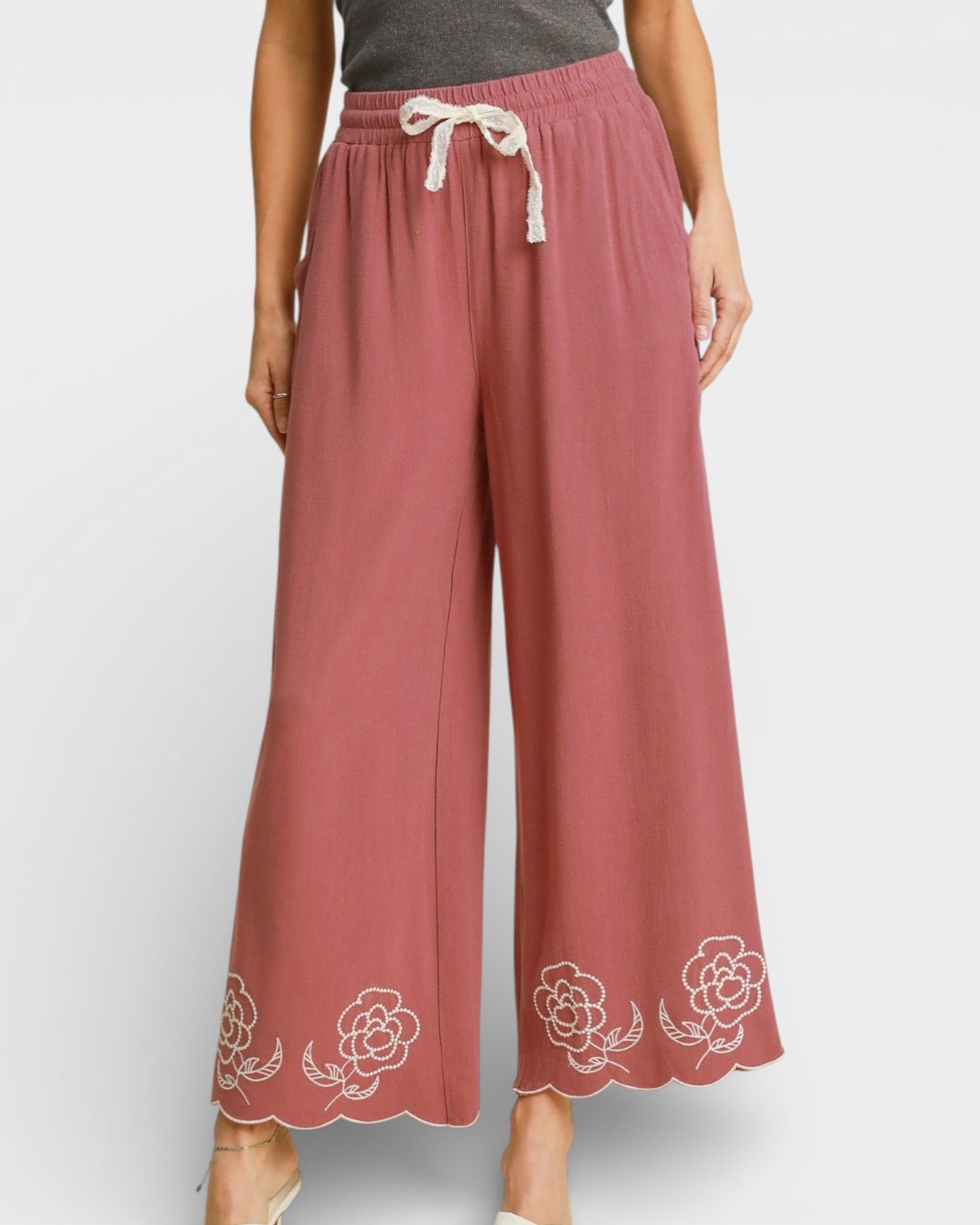 Pink pants with floral embroidery on a white background