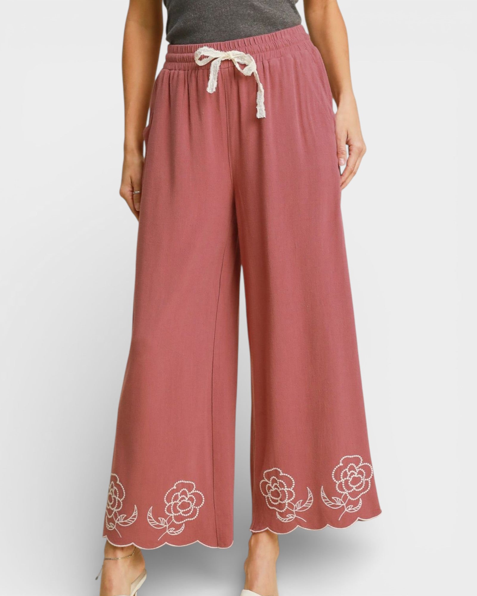 Pink pants with floral embroidery on a white background