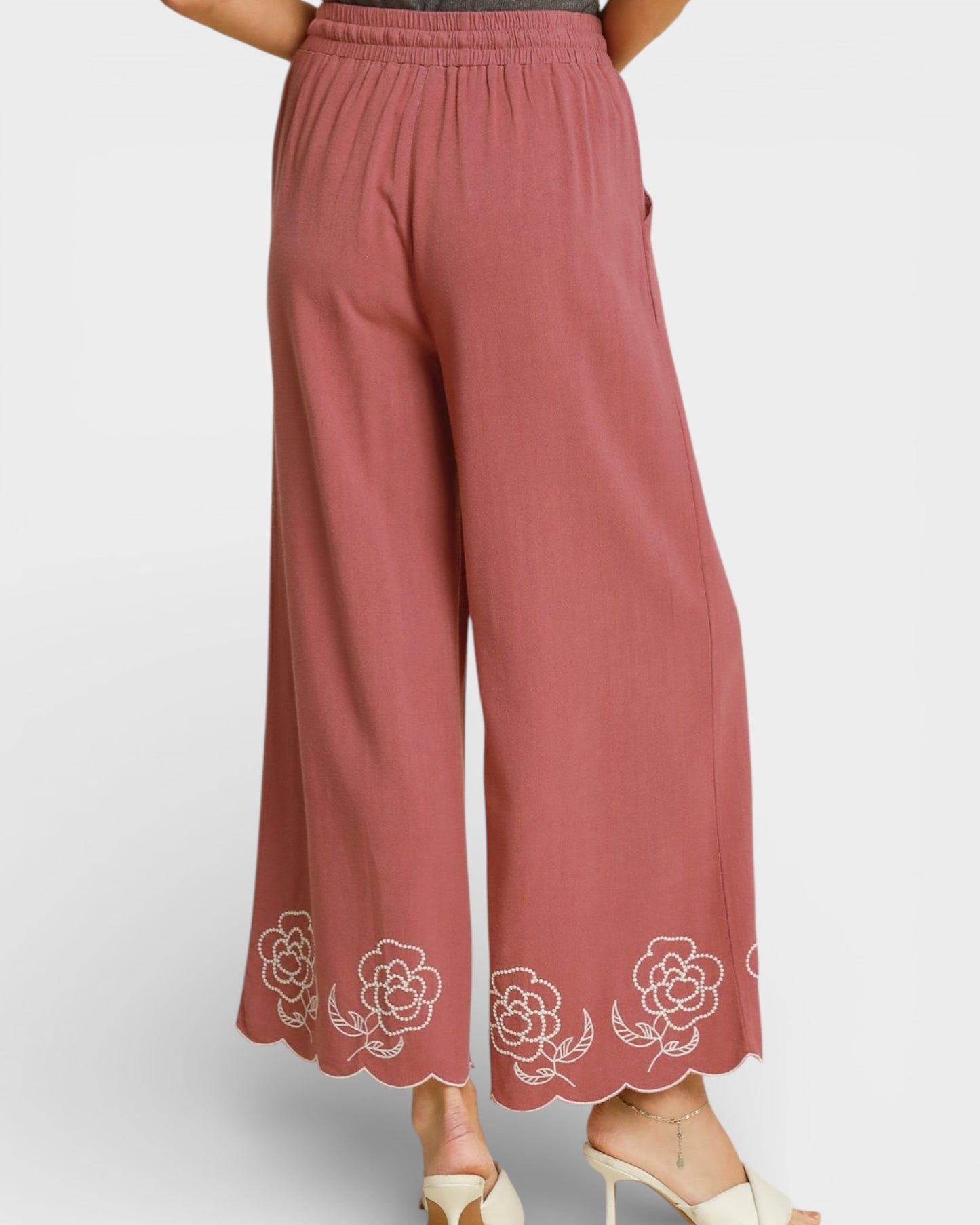 Pink pants with floral embroidery on a light gray background