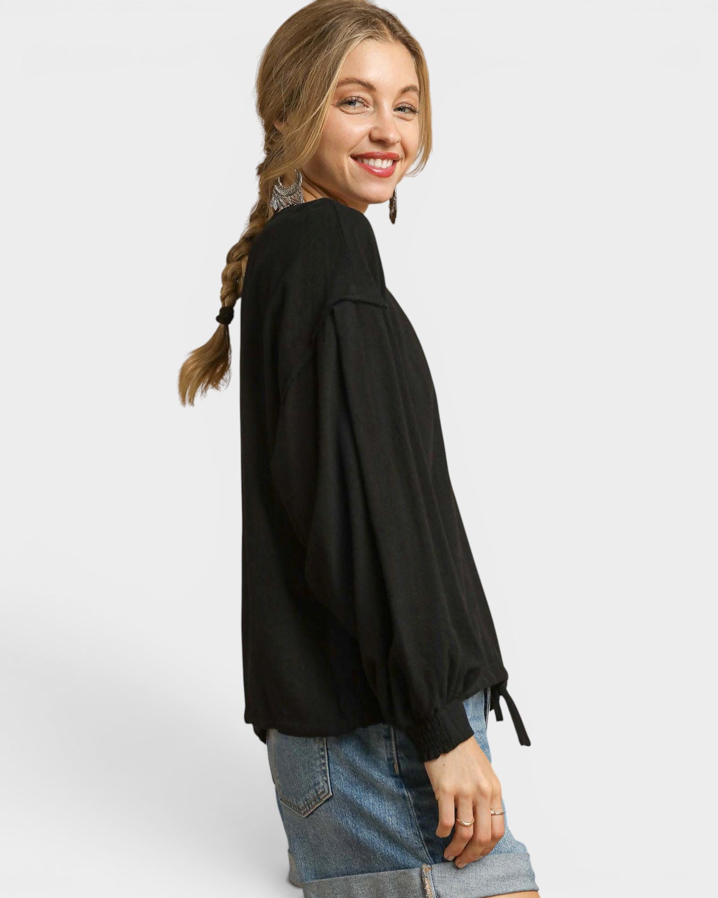 Woman wearing a black blouse and denim shorts on a white background